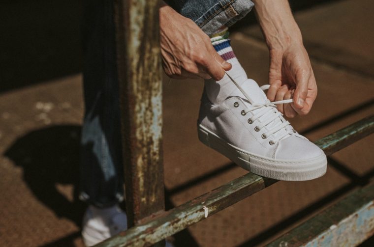 Model hands fixing laces on white sneaker